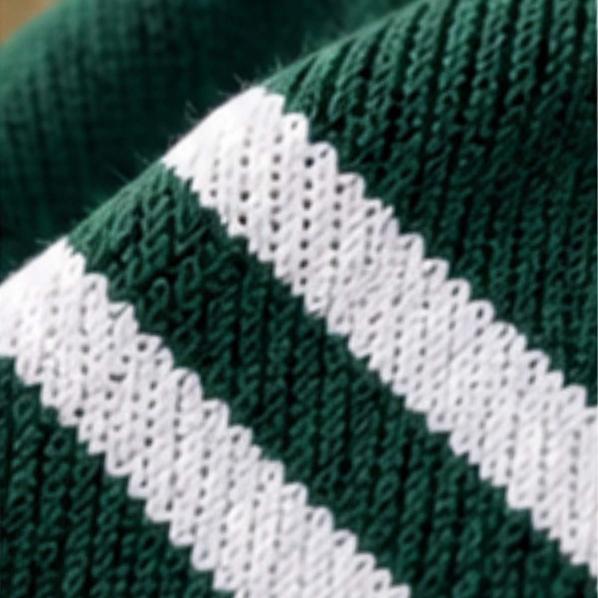 Close-up of a knitted fabric with dark green and white horizontal stripes.