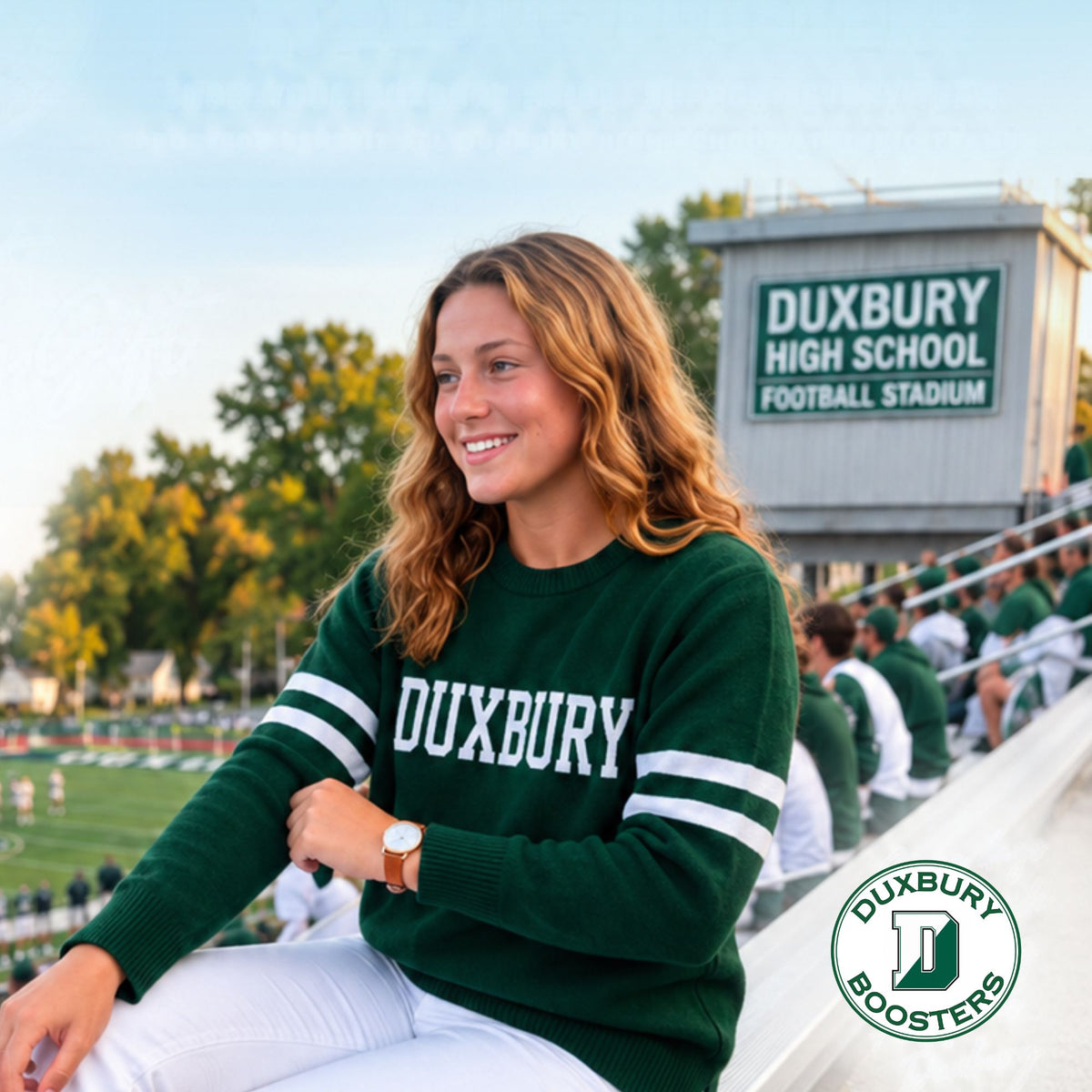 Woman in green sweater with "Duxbury" in white letters across the chest at Duxbury High School football stadium.