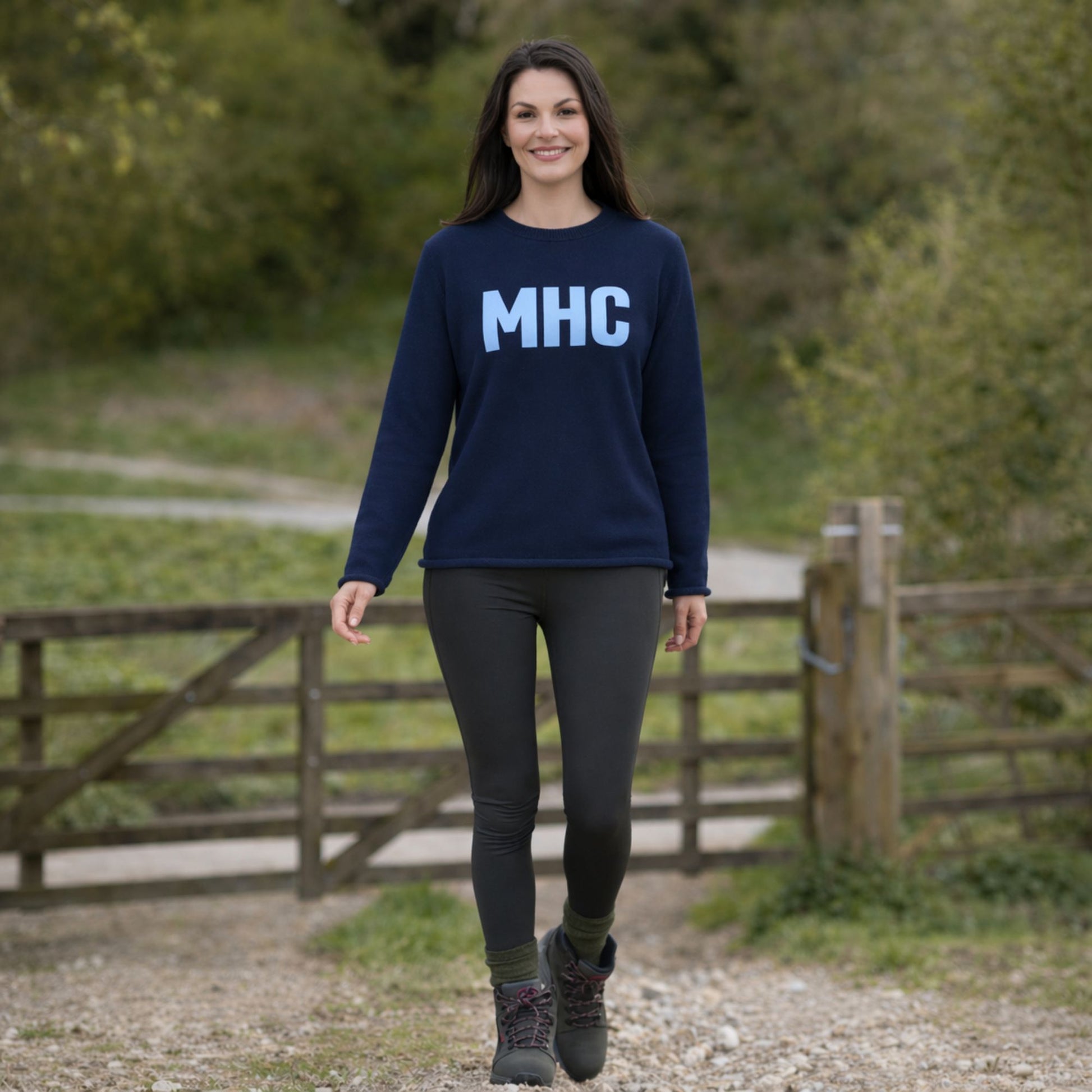 Woman wearing a navy blue sweatshirt with 'MHC' on it, standing outdoors.