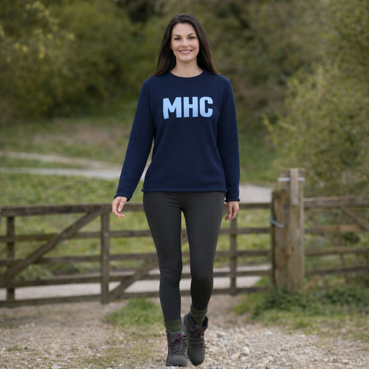 Woman wearing a navy blue sweatshirt with 'MHC' on it, standing outdoors.