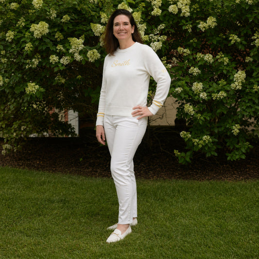 Woman in a white outfit standing outdoors with greenery in the background